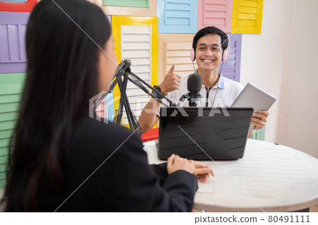 a man wearing headphones using a microphone with thumbs up gesture during a podcast a man wearing headphones using a microphone with thumbs up gesture during a podcast 80491111