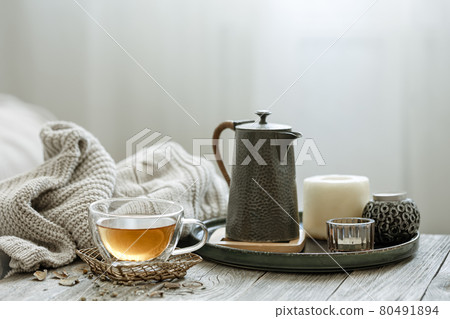 Home still life with a cup of tea, candles and a knitted element. 80491894