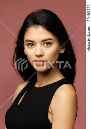 Close-up portrait. Young beautiful Caucasian woman in black clothes isolated over brown studio background. Close-up portrait. Young beautiful Caucasian woman in black clothes isolated over brown studio background. 80492581