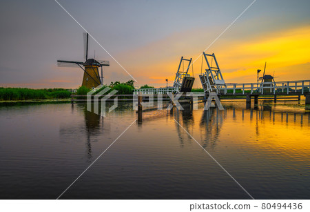 Sunset above a historic drawbridge and old windmills in Kinderdijk, Netherlands 80494436