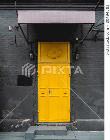 Building with black brick walls and bright yellow door. Colorful urban background. Building with black brick walls and bright yellow door. Colorful urban background. 80494583