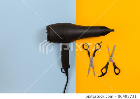 Styling hair with scissors, dryer and tools in barbershop on blue and yellow paper background top view mock-up 80495731