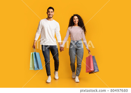 Portrait Of Happy Middle Eastern Couple Walking With Bright Shopping Bags Portrait Of Happy Middle Eastern Couple Walking With Bright Shopping Bags 80497680