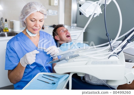 Female dentist with male patient in chair 80499260