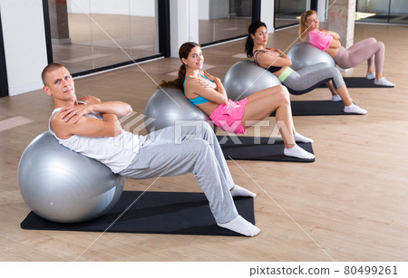 Sports people perform a back stretching exercise with a ball 80499261