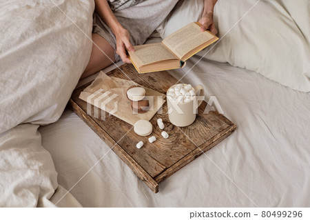 coffee in bed. shapely female legs in warm socks, wooden tray for breakfast in bed. two cups of coffee and marshmallows. the concept of cozy home. top view coffee in bed. shapely female legs in warm socks, wooden tray for breakfast in bed. two cups of coffee and marshmallows. the concept of cozy home. top view 80499296