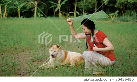 Portrait of a young Asia woman was under a banana leaf taking shelter from the rain in the green garden background Portrait of a young Asia woman was under a banana leaf taking shelter from the rain in the green garden background 80499490