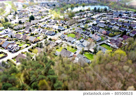 Aerial view of a housing estate on the outskirts of the big city Wolfsburg in Germany with a forest in the foreground, blurred by tilt shift effect Aerial view of a housing estate on the outskirts of the big city Wolfsburg in Germany with a forest in the foreground, blurred by tilt shift effect 80500028