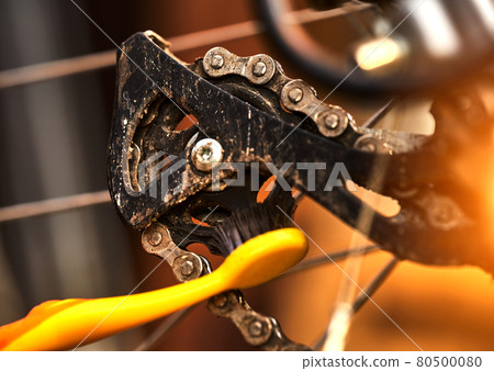 Cleaning the rear sprocket by a toothbrush at on the derailleur of a sporty bicycle with gears Cleaning the rear sprocket by a toothbrush at on the derailleur of a sporty bicycle with gears 80500080