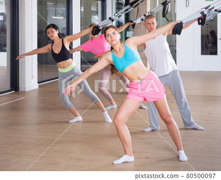 Sports people perform an exercise for stretching muscles using a special suspended structure 80500097