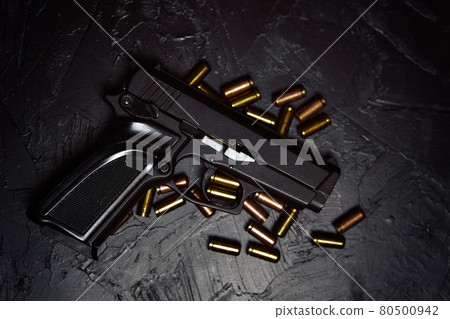 Pistol with cartridges on black concrete table. 80500942