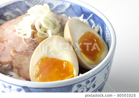 A steaming roast pork bowl topped with shredded cabbage and topped with green onions is photographed on a white background. A steaming roast pork bowl topped with shredded cabbage and topped with green onions is photographed on a white background. 80501028