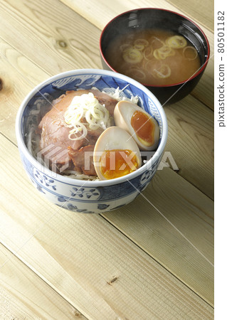 A set of steaming roast pork bowl and miso soup topped with shredded cabbage, miso balls and green onions 80501182
