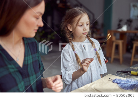 Flourist shop with different kinds of dryed flowers. Young happy confident specialist is working with her female kid. Flourist shop with different kinds of dryed flowers. Young happy confident specialist is working with her female kid. 80502005