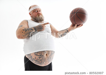 bearded fat caucasian tattoed man with basketball ball in white background. He is funny and happy bearded fat caucasian tattoed man with basketball ball in white background. He is funny and happy 80502007