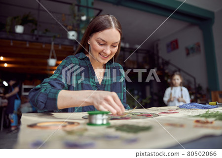 Flourist shop with different kinds of dryed flowers. Young happy confident specialist is working with her female kid. Flourist shop with different kinds of dryed flowers. Young happy confident specialist is working with her female kid. 80502066