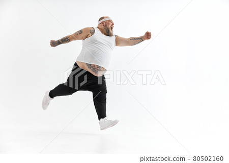Happy fat man with big belly and tattoes in sports wear posing on white background 80502160