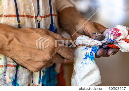 Closeup of hand mixing paint on palette at workshop 80502227