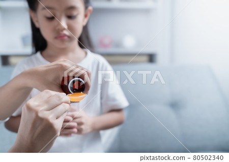 Mother is giving medicine to her sick daughter. 80502340