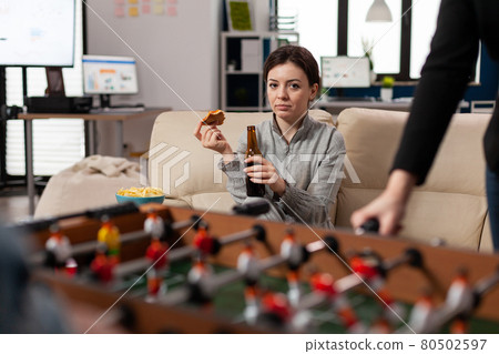 Woman sitting at foosball table at office after work 80502597