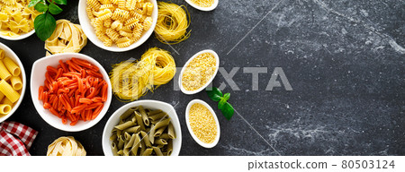 Pasta. Various kinds of uncooked pasta and noodles over stone background, top view with copy space for text. Italian food culinary concept. Collection of different raw pasta on cooking table 80503124