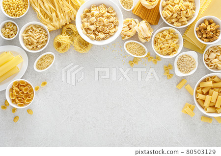 Pasta. Various kinds of uncooked pasta and noodles over stone background, top view with copy space for text. Italian food culinary concept. Collection of different raw pasta on cooking table Pasta. Various kinds of uncooked pasta and noodles over stone background, top view with copy space for text. Italian food culinary concept. Collection of different raw pasta on cooking table 80503129
