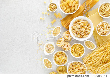Pasta. Various kinds of uncooked pasta and noodles over stone background, top view with copy space for text. Italian food culinary concept. Collection of different raw pasta on cooking table Pasta. Various kinds of uncooked pasta and noodles over stone background, top view with copy space for text. Italian food culinary concept. Collection of different raw pasta on cooking table 80503131
