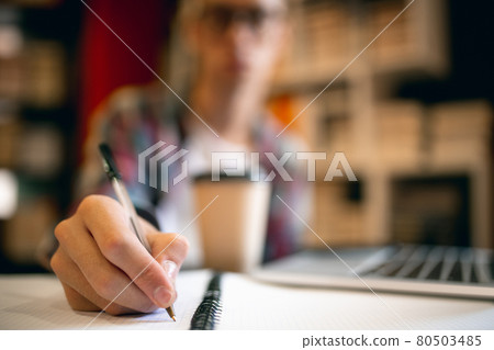 One young caucasian guy, student sitting at table with laptop over home or library background. 80503485