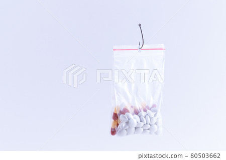 Colored Pills or Tablets Hanging in Small Ziplock Bag on a Fishing Hook Colored Pills or Tablets Hanging in Small Ziplock Bag on a Fishing Hook 80503662
