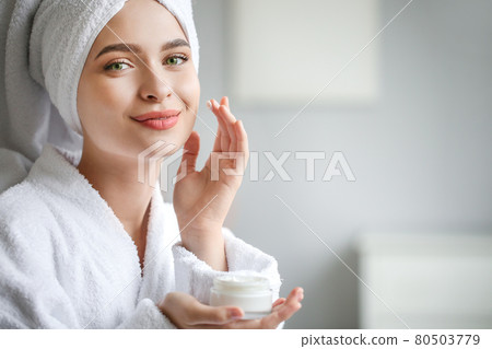 Beautiful woman with green eyes coming out of the bath with cream in her hands. Beautiful woman with green eyes coming out of the bath with cream in her hands. 80503779