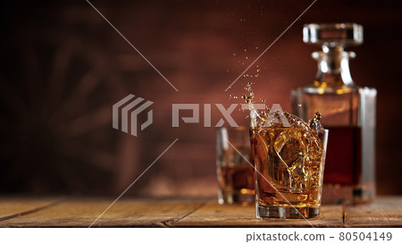 Freeze motion of ice cube falling into whisky shot Freeze motion of ice cube falling into whisky shot 80504149