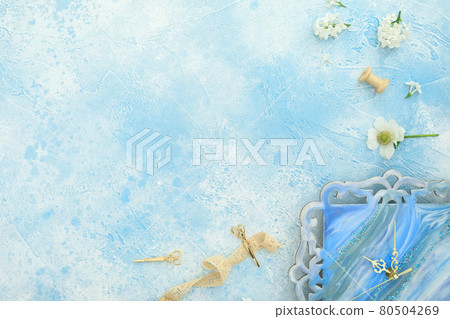 Composition of flowers and resin art wall clock on blue. Flat lay, top view. Copy space 80504269