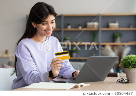 Smiling lady using laptop and credit card at home 80504487