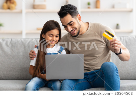 Happy family using computer and credit card at home 80504508