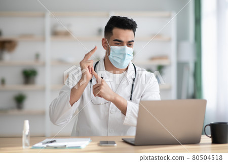 Arab doctor in face mask having video chat with patient Arab doctor in face mask having video chat with patient 80504518