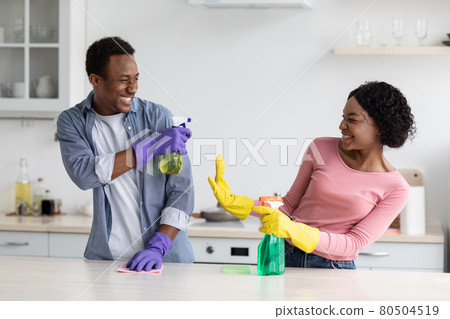 Cheerful black house-keepers having fun while cleaning kitchen Cheerful black house-keepers having fun while cleaning kitchen 80504519