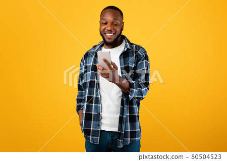 Joyful African American Male Holding Cellphone Using Mobile App, Studio Joyful African American Male Holding Cellphone Using Mobile App, Studio 80504523
