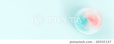 Colorful pastel color rainbow spiral plastic toy on turquoise background on podium 80505147