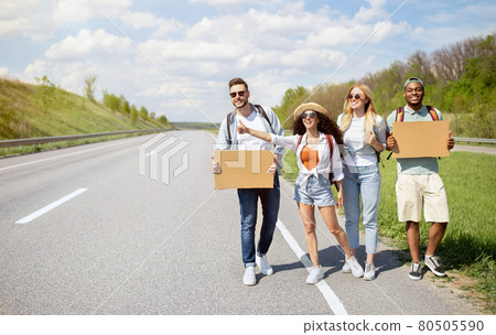 Group of multiethnic friends with empty signs hitchhiking on road, catching ride, traveling by autostop, copy space Group of multiethnic friends with empty signs hitchhiking on road, catching ride, traveling by autostop, copy space 80505590