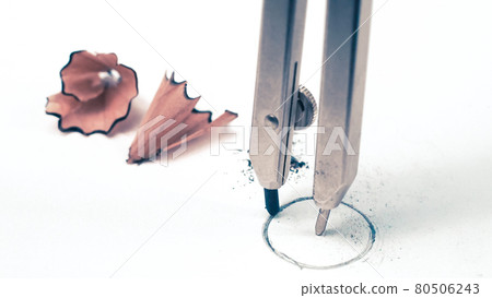 Macro detail closeup of a rotring school geometry drawing compass drafting a precise mathematical round circle on white student paper with a graphite lead tip with study pencil shavings in the Macro detail closeup of a rotring school geometry drawing compass drafting a precise mathematical round circle on white student paper with a graphite lead tip with study pencil shavings in the 80506243