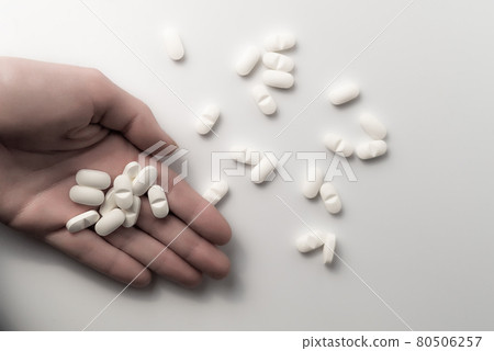 Hand holding many dosages of chemical opioids medical pills and a pile of pharmaceutical medication on clean white background with copyspace - Concept of abuse addiction, antibiotic or healthcare 80506257