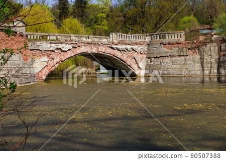 Old arched brick bridge across a pond in Sharovka Palace park in in Kharkov region, Ukraine Old arched brick bridge across a pond in Sharovka Palace park in in Kharkov region, Ukraine 80507388