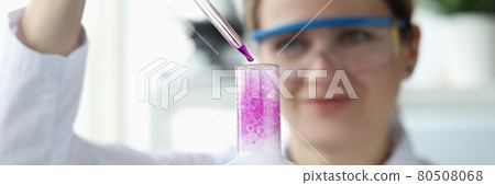 Woman scientist dripping reagent into flask with foamy water 80508068