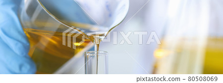 Scientist chemist pouring oil from flask into glass closeup 80508069