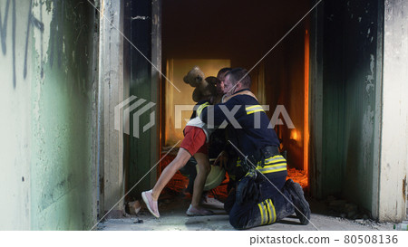 Firemen speaking and giving toy to girl 80508136