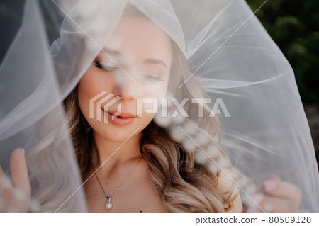 beautiful bride with long wavy hair under the veil. Wedding make-up.  80509120