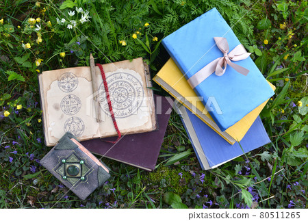 Still life with books and diary with wiccan holidays on pages laying on green grass lawn outside. Vintage romantic and educational concept Still life with books and diary with wiccan holidays on pages laying on green grass lawn outside. Vintage romantic and educational concept 80511265