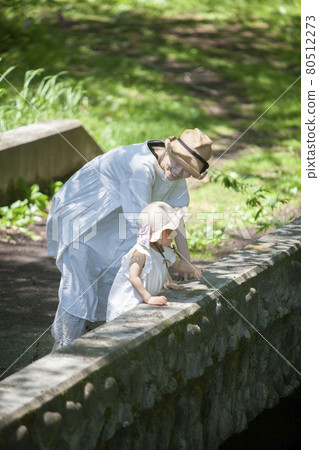 Parents and children looking into the river from the bridge 80512273