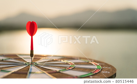 Soft focus shot red darts arrows in the target center on dark sky background. Business target or goal success and winner concept. Soft focus shot red darts arrows in the target center on dark sky background. Business target or goal success and winner concept. 80515446