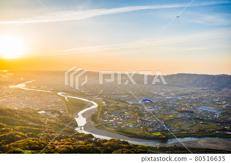 An aerial view of the sunset seen from above Mt. Yuri in Kinokawa City, Wakayama Prefecture, from a paraglider. Autumn, November. 80516635